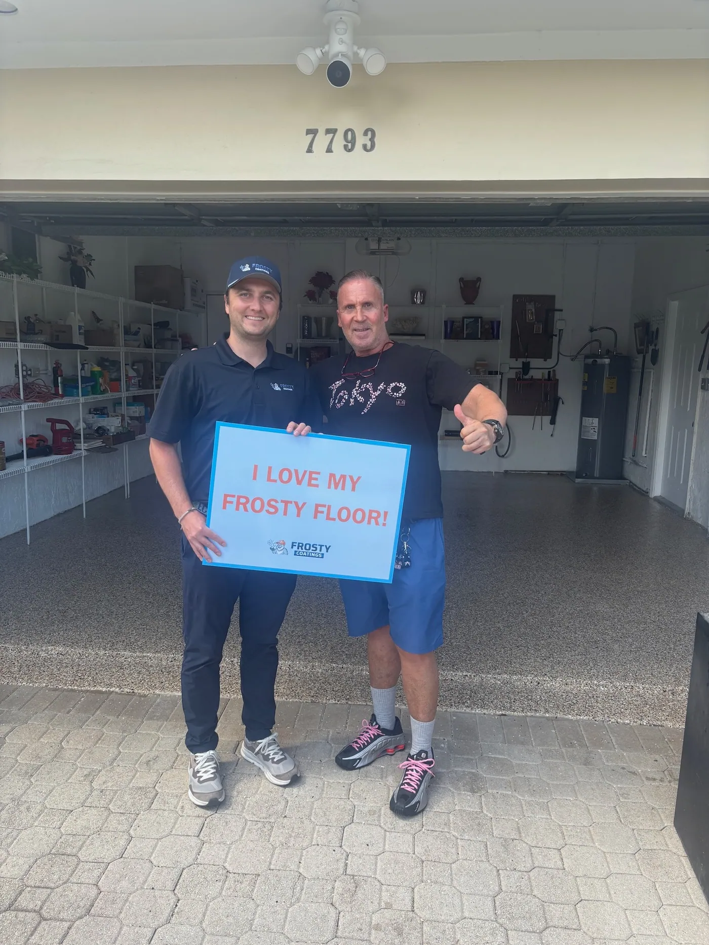 A customer and a Frosty Coatings installer with the sign on a new garage floor