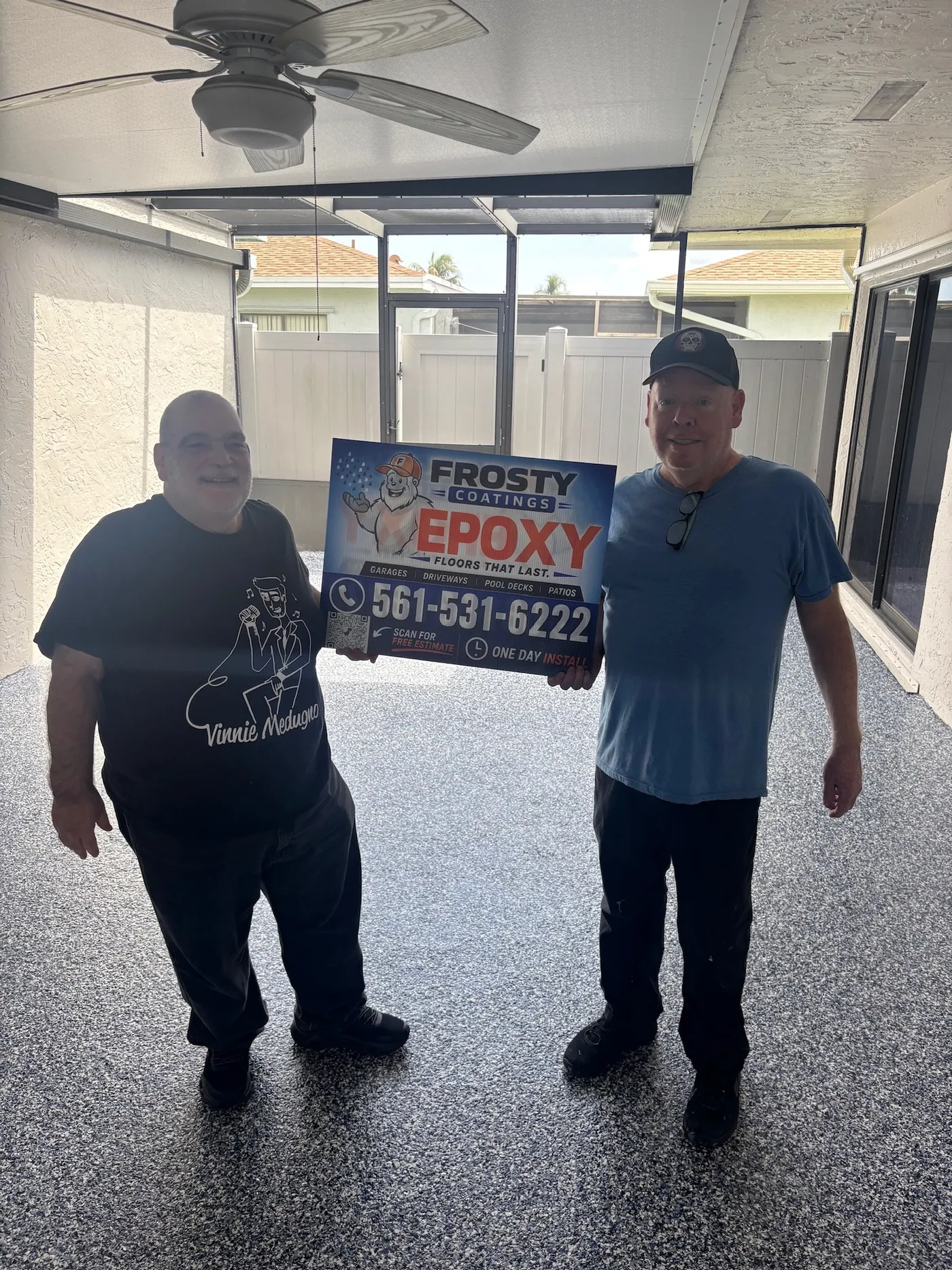 Two customers holding a Frosty Coatings sign on their finished patio