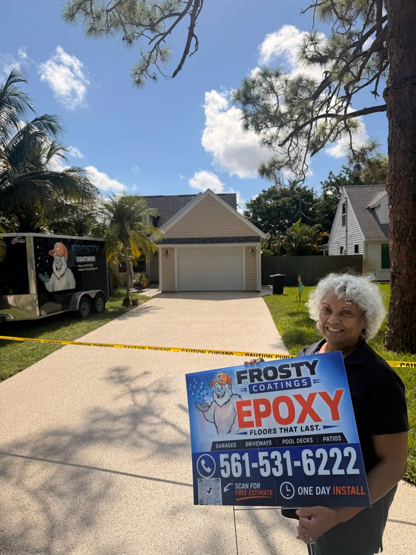A customer holding a Frosty Coatings sign on her newly coated driveway