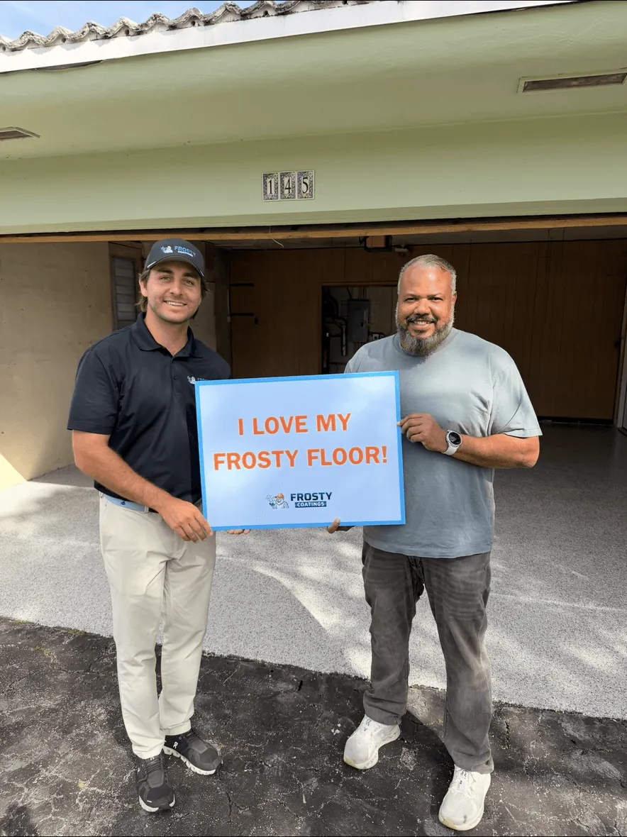 A customer holding the I Love My Frosty Floor sign at his open garage door