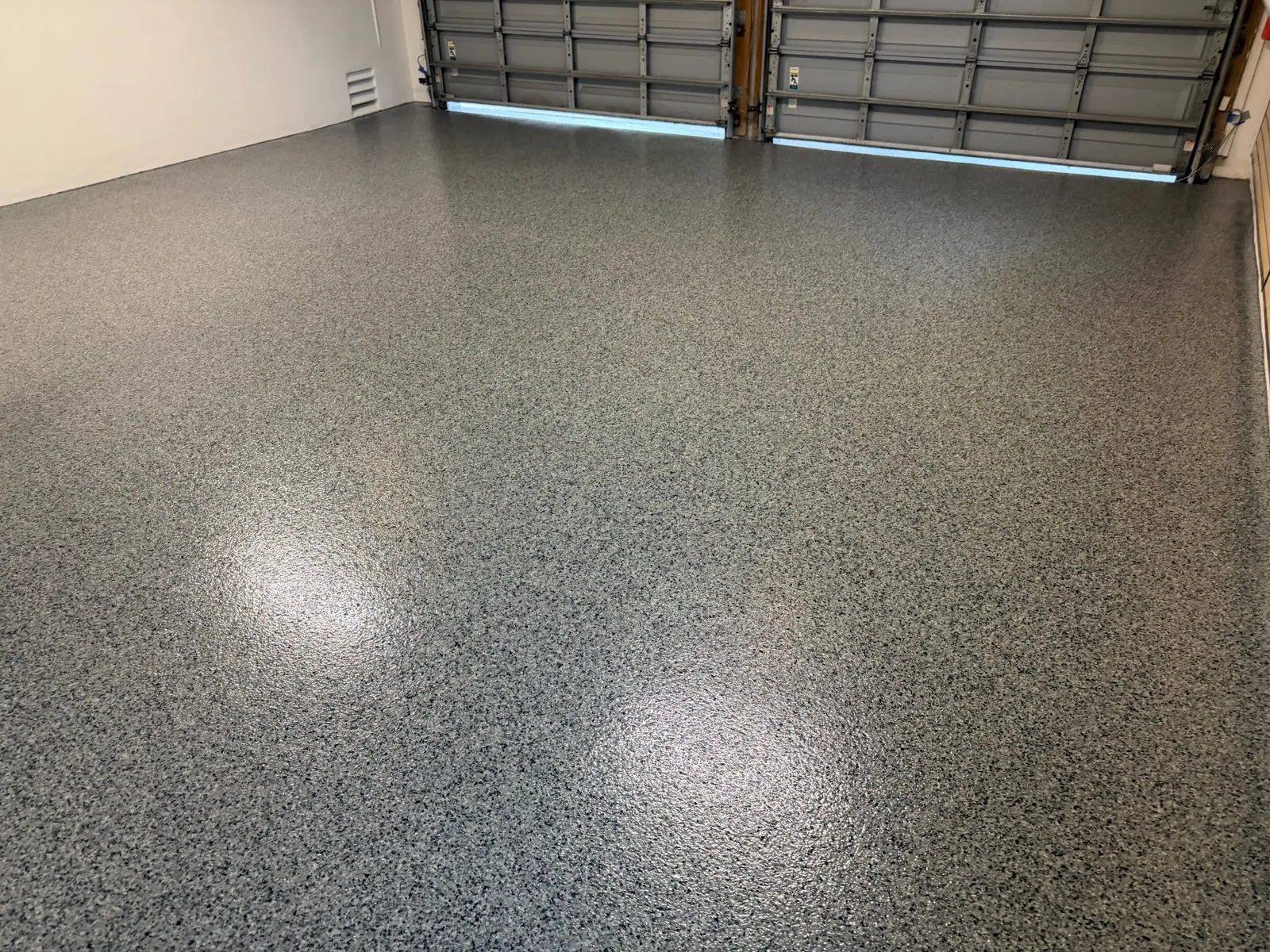 Glossy grey flake garage floor with the doors open to daylight
