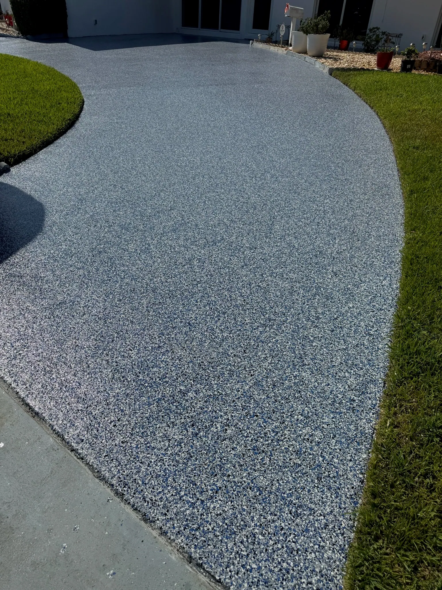Curved residential driveway finished in a light grey flake system